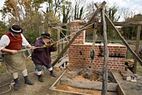 Wheelwright Paul Zelesnikar, left, and founder Mike Noftsger use a block and tackle to lift a coehorn mortar from its mold.